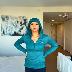 Adidas lightweight waterproof jacket in teal. Two pockets with a hood.